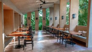 a row of tables and chairs in a room with trees at Hotel Maya Bell in Palenque