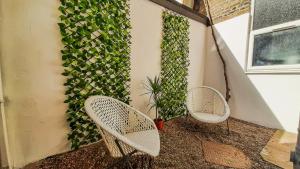 two white chairs sitting next to a wall with a plant at Stunning 2 bedrooms apartment in London