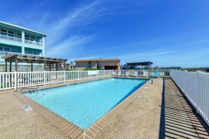 a swimming pool with a white fence and a building at Direct Beach Access Sunny Port Aransas Condo in Port Aransas