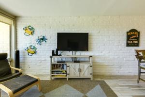 a living room with a tv on a white brick wall at Direct Beach Access Sunny Port Aransas Condo in Port Aransas