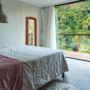 ein Schlafzimmer mit einem Bett und einem großen Fenster in der Unterkunft Casa Dinamarca in Santa Teresa