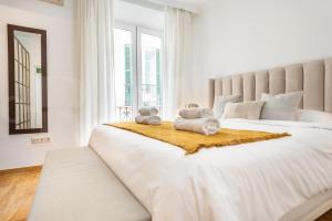 una camera da letto bianca con un grande letto con asciugamani sopra di Charming apartment with private patio by REMS a Málaga