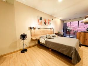 a bedroom with a bed and a desk and a window at Loft cerca del Palacio de Exposiciones NID102 By Roots Rentals in Medellín