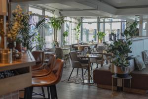 a restaurant with tables and chairs and plants at Hotel Steeds aan Zee in Katwijk aan Zee