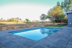 a swimming pool with a stone patio and a retaining wall at Eagle's Nest in Parys