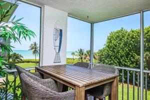 einen Holztisch und Stühle auf einem Balkon mit Meerblick in der Unterkunft Island Beach Club #320C in Sanibel