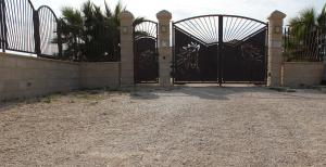 a gate to a house with palm trees behind it at B&B L'EDEN DI CAPO BIANCO in Montallegro