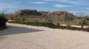 a gravel driveway with plants and mountains in the background at B&B L'EDEN DI CAPO BIANCO in Montallegro