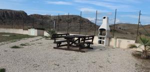a picnic table and benches in front of a fence at B&B L'EDEN DI CAPO BIANCO in Montallegro