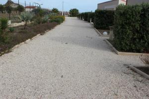 a gravel driveway with bushes and a house at B&B L'EDEN DI CAPO BIANCO in Montallegro