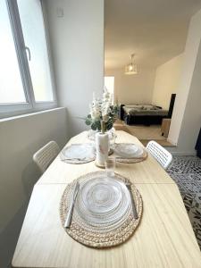 een eettafel met borden en bloemen erop bij Le Loft d'Azur - Cozy - Netflix in Fontainebleau