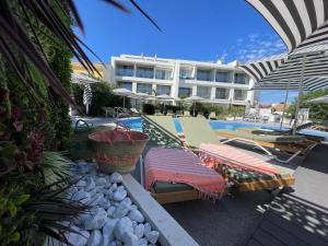 a swimming pool with two lounge chairs and a hotel at Hôtel Eve Cap d'agde Village Naturiste in Cap d'Agde