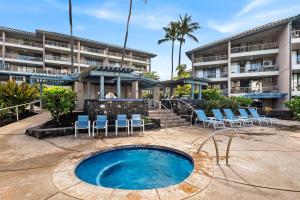 a swimming pool with chairs and a building at Kona Reef A36 in Kailua-Kona