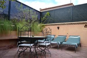 d'une terrasse avec une table, des chaises et une clôture. dans l'établissement Riad Charik, à Marrakech
