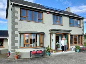 two people standing in the front of a house at Carrigadaggen Lodge in Ballynagrallagh