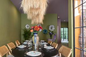 a dining room with a table and a vase with flowers at HOLT Art Deco Retreat in Vibrant 3 Bedroom Villa in San Miguel de Allende