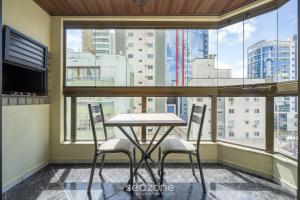a table and two chairs in a room with a large window at Apto em otima localização em Meia Praia EIO6031 in Meia Praia