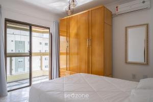 a bedroom with a bed and a wooden cabinet at Apto em otima localização em Meia Praia EIO6031 in Meia Praia