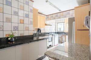 a kitchen with white cabinets and a black counter top at Apto em otima localização em Meia Praia EIO6031 in Meia Praia