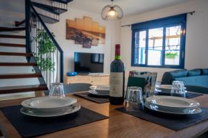 a bottle of wine sitting on a table with plates and glasses at Casa azul Agaete in Las Palmas de Gran Canaria