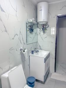 a white bathroom with a toilet and a sink at J&B Apparts Wifi in Mvolyé +2 photos