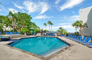 a swimming pool with blue lounge chairs and trees at Serenity at Moon Bay! in Key Largo