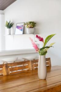 un vase blanc avec des fleurs posé sur une table dans l'établissement Hotel Por Qué No, à Uvita