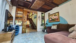 a living room with a couch and a television and a staircase at Manacá Suítes Prumirim in Ubatuba