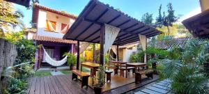 a patio with wooden tables and benches on a house at Pousada do Titi in Caraíva +16 photos