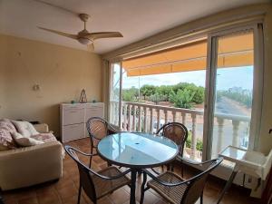 a living room with a table and chairs and a balcony at Agréable appartement avec piscine commune in San Pedro del Pinatar