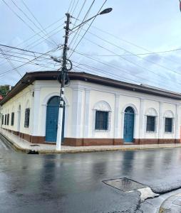 a white building with blue doors on a street at Hotel Boutique Casa Diriangen in Diriamba