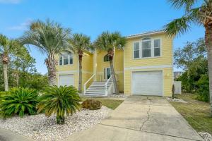 ein gelbes Haus mit Palmen und einer Auffahrt in der Unterkunft The Yellow House at Herons Walk in Pensacola