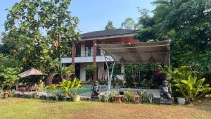 a house with a large umbrella in front of it at Little Bali Villa - Luxury Lake View at Bogor in Kalisuren 2