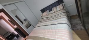a bed with a striped blanket on it in a bedroom at Appart à Malaga Beach Mansouria in Mansouria