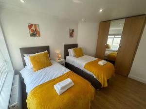 1 dormitorio con 2 camas con sábanas amarillas y espejo en 2 bedroom, Parking, Hounslow St, en Londres