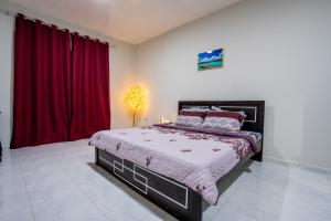 a bedroom with a large bed with red curtains at BAITH AL JANNAH L L C - Working Professional - Peaceful Daily and Weekly Room in Abu Dhabi
