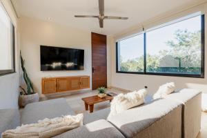 a living room with a couch and a large window at Beautiful 3 BDR, 3 BA Modern Condo MINUTES From Beach in Tulum