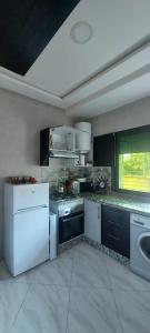 a large kitchen with white appliances and a window at Appartement meublé in Ville Nouvelle