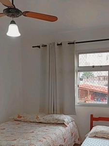 a bedroom with a ceiling fan and a window at AP Ventidor in Guarapari +8 photos