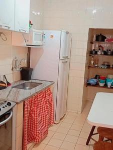 a kitchen with a white refrigerator and a sink at AP Ventidor in Guarapari