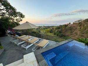 a pool with two lounge chairs and an umbrella at Villa Bukit Sing Sing in Singaraja