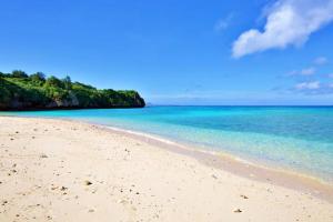 a sandy beach with blue water and trees in the background at ocean terrace SESOKO 301 in Ufugumui