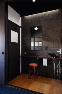 une salle de bain avec un tabouret et un mur noir dans l'établissement Tsuyukusa-an, à Kyoto