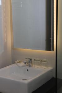 a white sink with a mirror and two glasses on it at Gets Hotel in Malang
