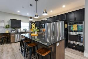 a kitchen with black cabinets and a large island with bar stools at Livin' The Dream- Indoor Outdoor pool & Private Hot Tub in Branson