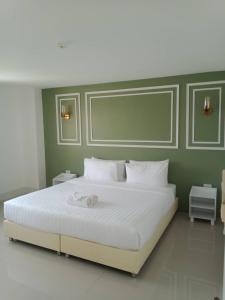 a bedroom with a large white bed with green walls at Regent Lodge Lampang in Lampang