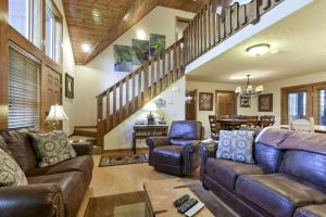 a living room with leather furniture and a staircase at Sooner Settle Lodge 4 King Rooms Stonebridge in Reeds Spring +57 photos