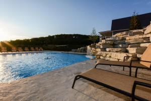 a swimming pool with a bench next to a stone wall at Journey's Remedy -Lake View Sleeps 30 in Branson