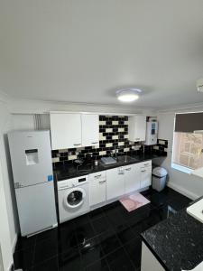 ThamesmeadにあるThamesNicePropertyの白の家電製品と黒の床が備わるキッチン
