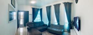 a living room with blue curtains and a couch at Fnaa Tg Bidara Malacca Guest House - 3BR Fully Aircond in Masjid Tanah +11 photos